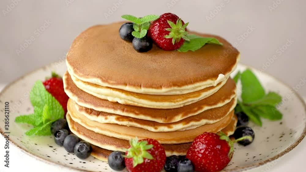 Pancake with strawberry, blueberry and mint in ceramic dish on rotated on light table, close up. Pancake with strawberry, blueberry and mint in ceramic dish on rotated on light table, close up.