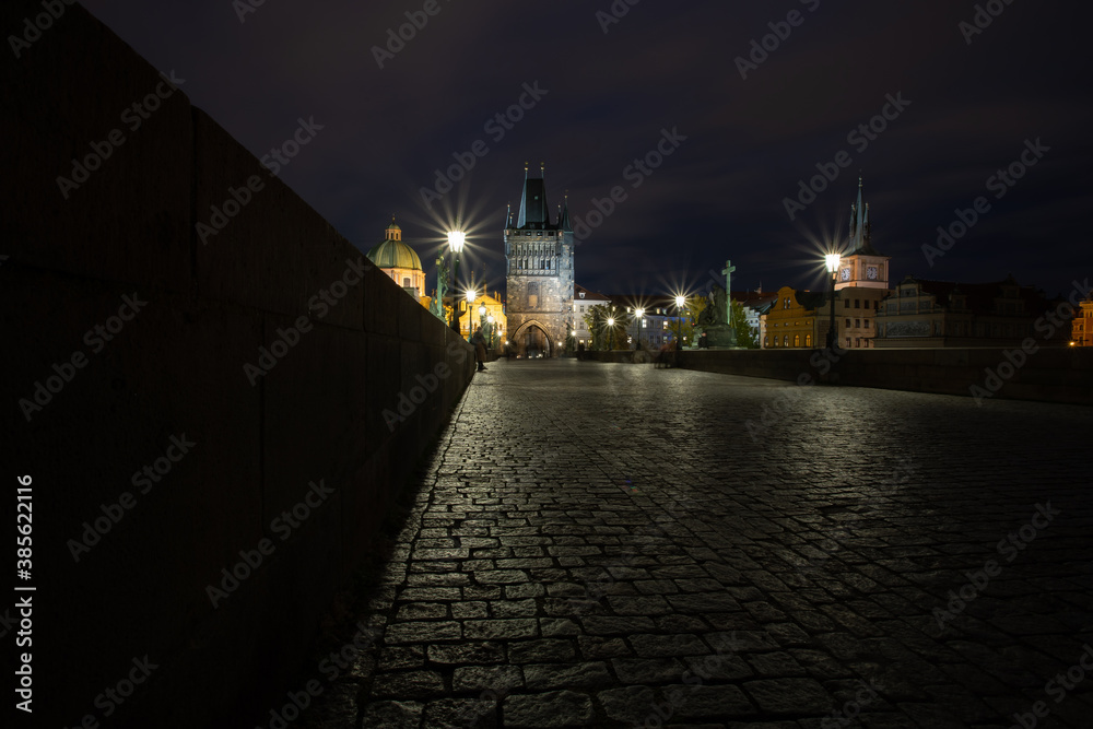 illuminated by the light of Charles Bridge. monument from 1402 in the center of prague on the flowing river vltava in the czech republic paving blocks for sidewalks and light from street lighting on 