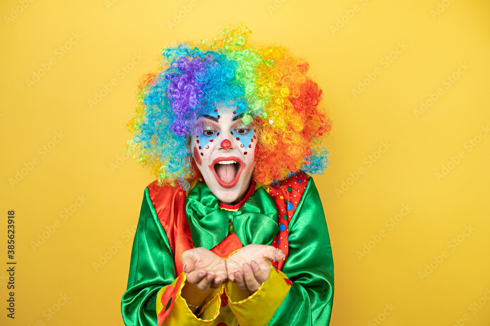 Clown standing over yellow insolated yellow background Smiling with hands palms together receiving or giving gesture. Hold and protection Clown standing over yellow insolated yellow background Smiling with hands palms together receiving or giving gesture. Hold and protection