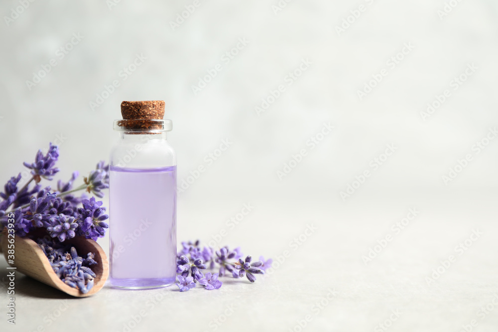 Bottle of essential oil and lavender flowers on light stone table. Space for text - obrazy, fototapety, plakaty 