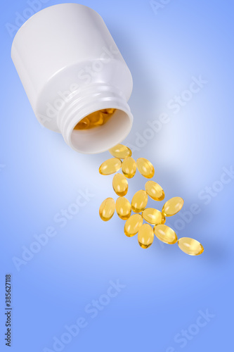 Vitamin D capsules scattered on a blue background. Food additive