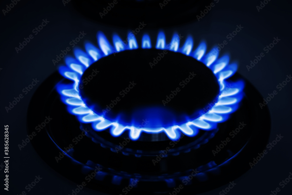 Gas burner of modern stove with burning blue flame at night, closeup Gas burner of modern stove with burning blue flame at night, closeup