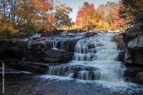 Fototapeta Naklejka Na Ścianę i Meble -  Peak fall foliage surrounds beautiful cascading lower Shohola Falls on an Autumn morning in the Pennsylvania Poconos