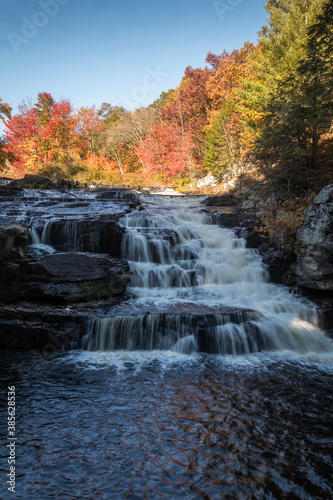 Peak fall foliage surrounds beautiful cascading lower Shohola Falls on an Autumn morning in the Pennsylvania Poconos