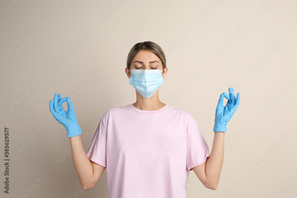 Woman in protective mask meditating on beige background. Dealing with stress caused by COVID‑19 pandemic Woman in protective mask meditating on beige background. Dealing with stress caused by COVID‑19 pandemic
