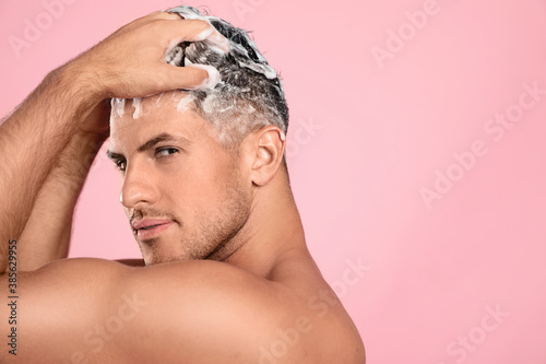 Handsome man washing hair on pink background. Space for text