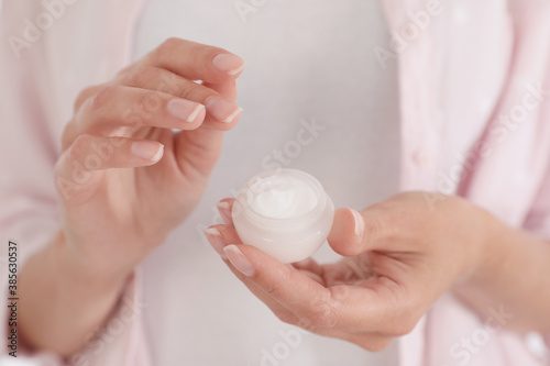 Woman holding open jar with cream, closeup