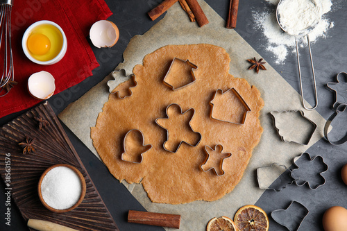 Raw dough, different cutters and ingredients for Christmas cookies on grey table, flat lay