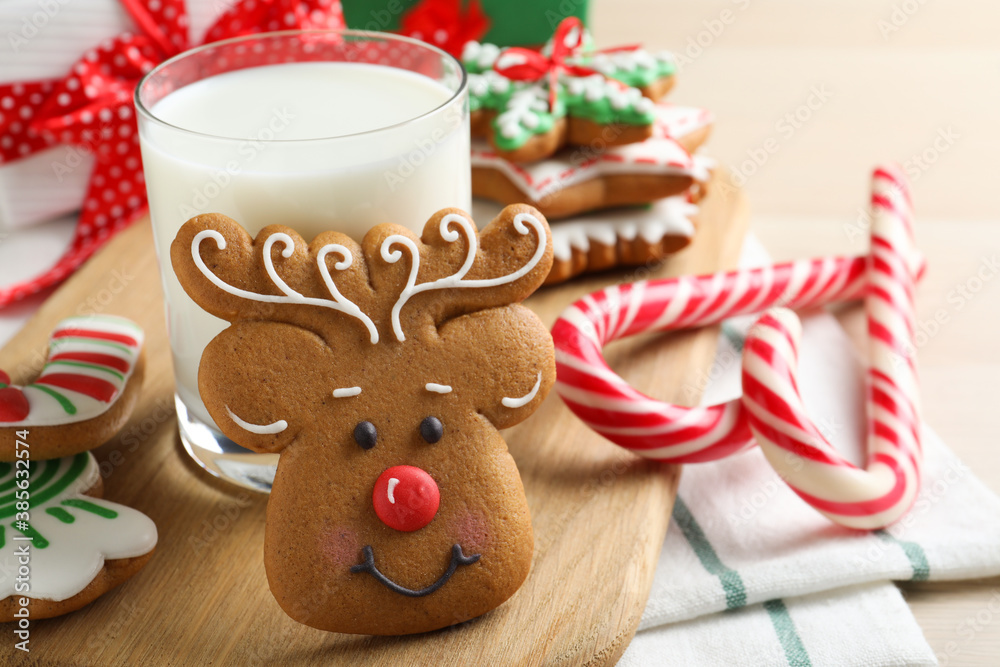 Decorated Christmas cookies and glass of milk on wooden table, closeup