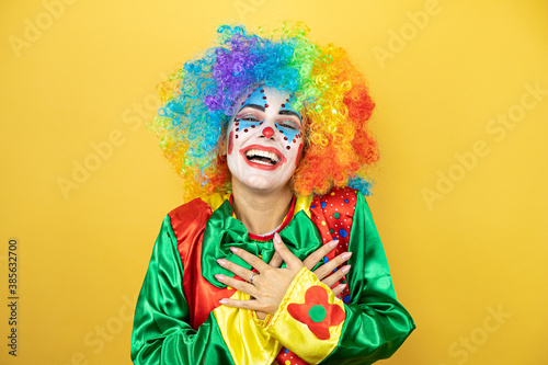 Clown standing over yellow insolated yellow background smiling with her hands on her chest and grateful gesture on her face.
