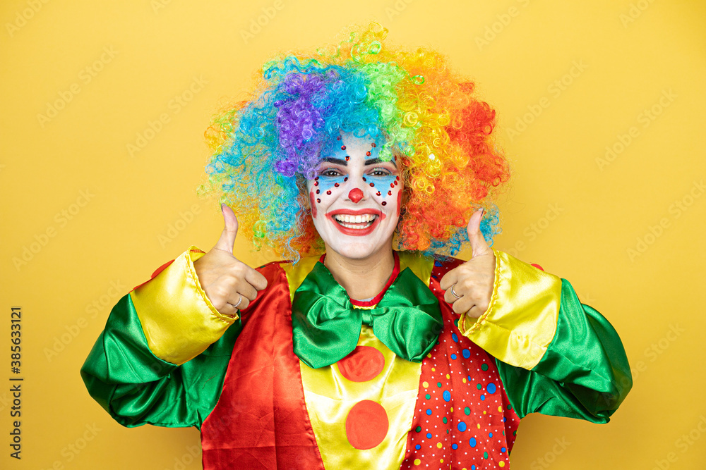 Clown standing over yellow insolated yellow background smiling and doing the ok signal with her thumbs Clown standing over yellow insolated yellow background smiling and doing the ok signal with her thumbs