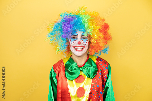 Clown standing over yellow insolated yellow background smiling.