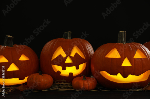 Glowing jack o'lanterns on table in darkness. Halloween decor