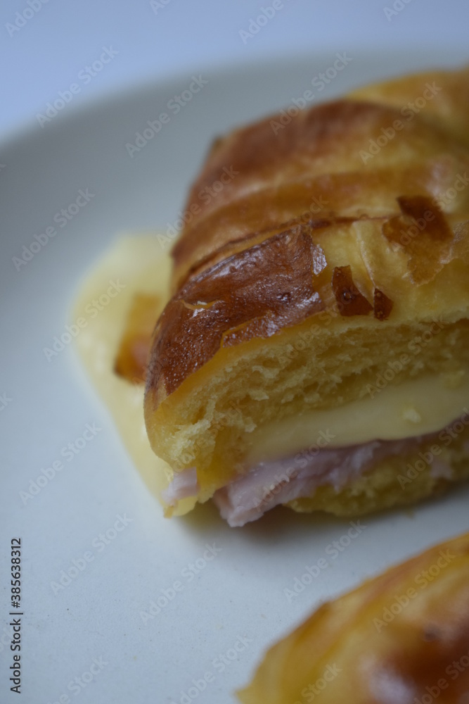 Close up of ham and cheese croissant served on white plate Close up of ham and cheese croissant served on white plate