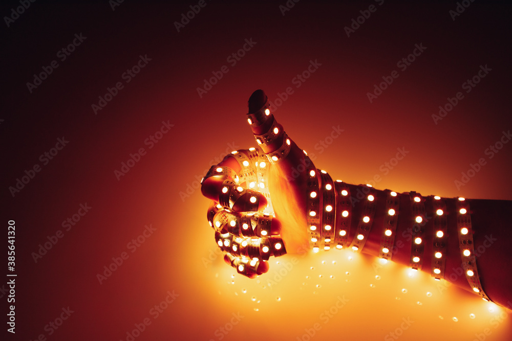 thumbs up hand covered with orange led lights, illuminated background