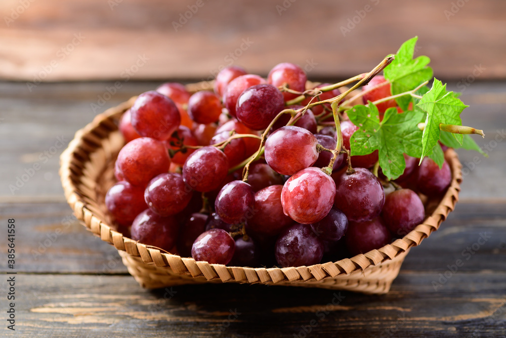 Fresh red grapes fruit in a basket on wooden background Fresh red grapes fruit in a basket on wooden background
