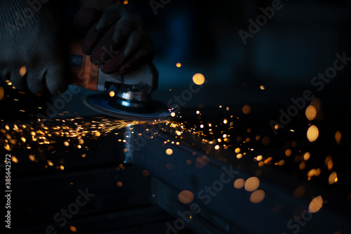 Grinding metal with a grinder. Working in a metal processing workshop. Cleaning the steel seam. The man works with an electric tool. Sparks from metal heating.