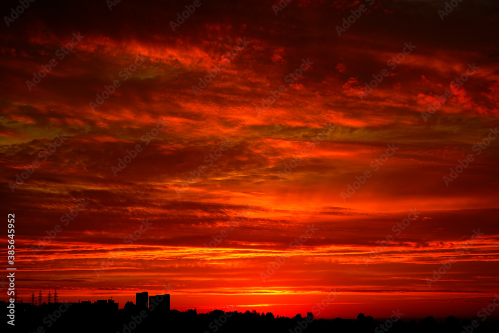   Red sunset over the city. Black red abstract background. Dramatic sky. Dark red horror background. Blood red sunset. Armageddon. Silhouettes of buildings.