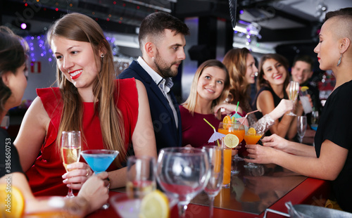 Portrait of happy young woman with colleagues enjoying corporate party at bar