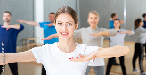 Portrait of dancing girl practicing vigorous swing during group training in dance studio