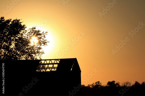 sunset in the countryside with a shed and tree silhouette's. Out in the country by Lyon's Kansas USA. photo