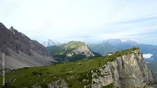 Aerial of a small house (refugio Tissi) on a cliff mountain ridge, dolomites italy photo