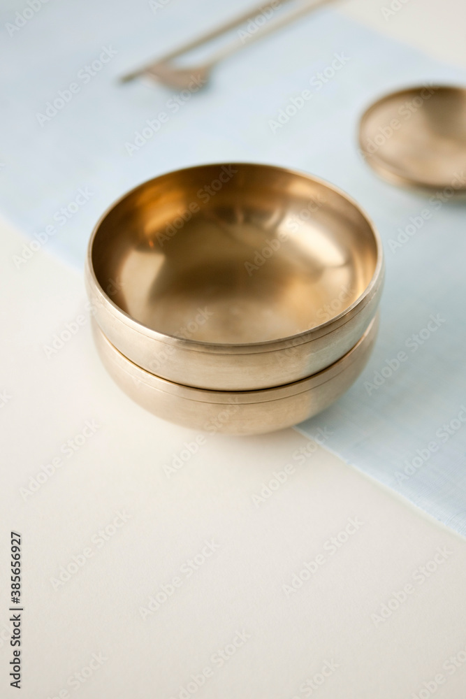 Korean traditional brassware plate setting on blue ramie cloth.
