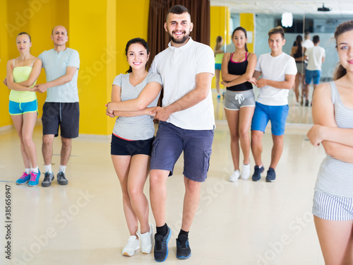 Young positive sporty girls and men learning salsa steps