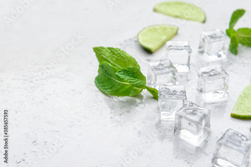 Ice cubes, mint and lime on light background