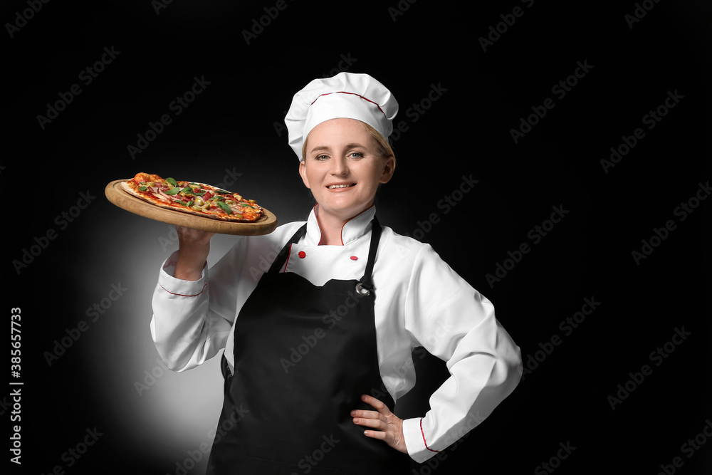 Mature female chef with tasty pizza on dark background Mature female chef with tasty pizza on dark background