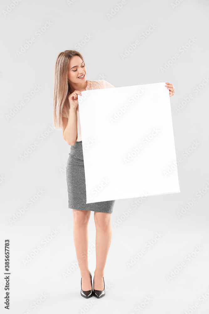 Young woman with blank paper sheet on light background Young woman with blank paper sheet on light background