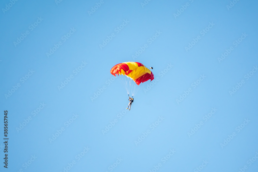 One parachutist floats slowly at low altitude on the background of clear sky One parachutist floats slowly at low altitude on the background of clear sky
