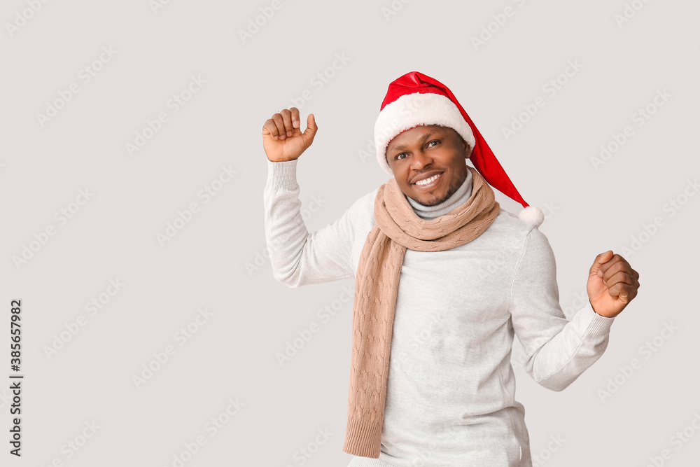 African-American man in Santa hat on light background African-American man in Santa hat on light background