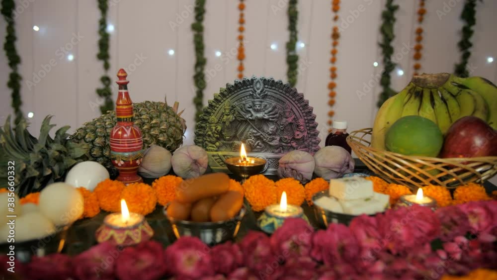 Bengali woman's hand placing a burning oil lamp in front of Ma Durga's