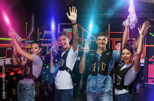 young happy people with laser guns having fun together in dark labyrinth