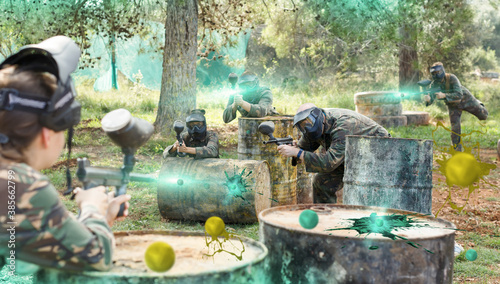 Team of friends paintball players playing together in battle in forest outdoors