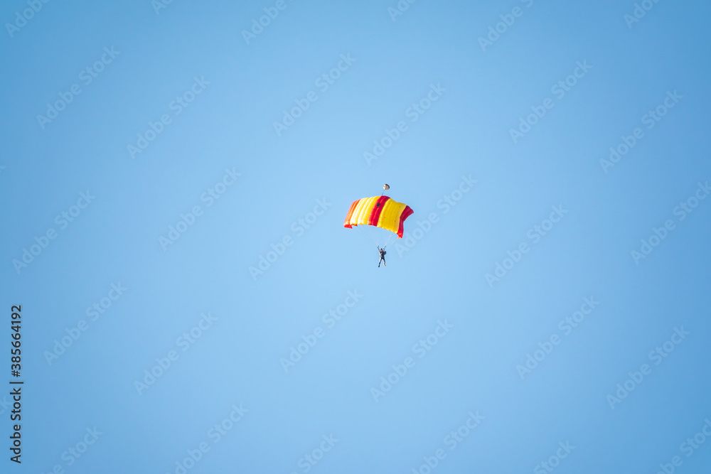 One parachutist floats slowly at low altitude on the background of clear sky One parachutist floats slowly at low altitude on the background of clear sky