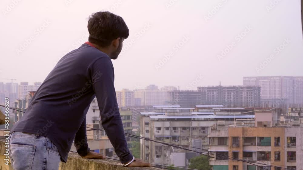 boy on tarace checking smart watch looking over bulings india boy on tarace checking smart watch looking over bulings india