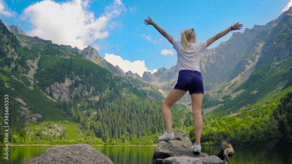 Beautiful Girl posing at lovely Mountain Lake with green trees and blue sky mountain view Beautiful Girl posing at lovely Mountain Lake with green trees and blue sky mountain view