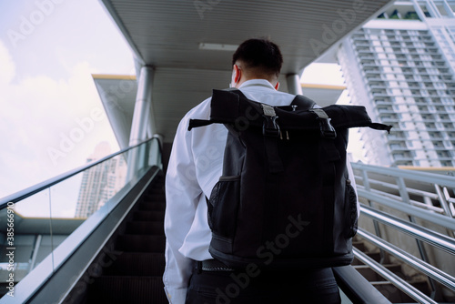 Business man carry big bag using escalator to get in office building.