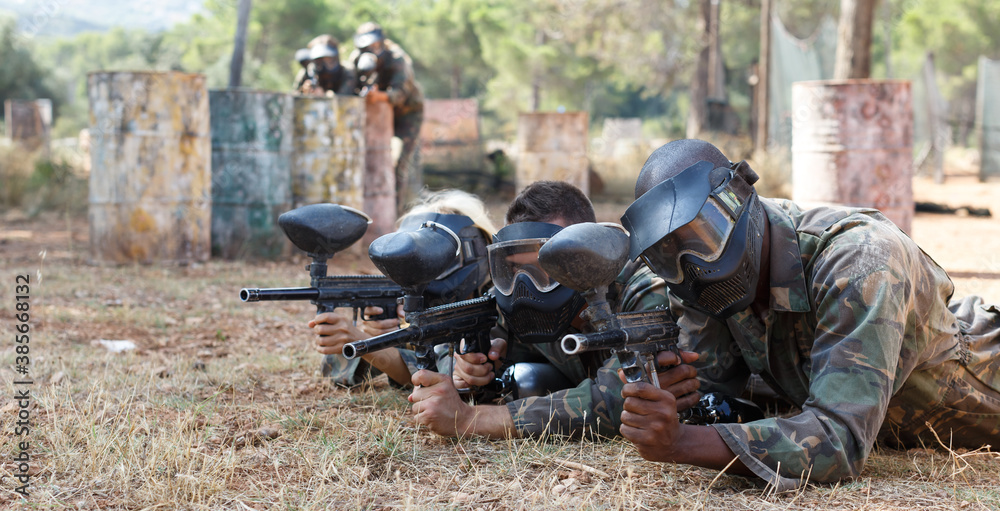 Fototapeta premium Portrait of team of adult people playing on paintball battlefield area outdoor
