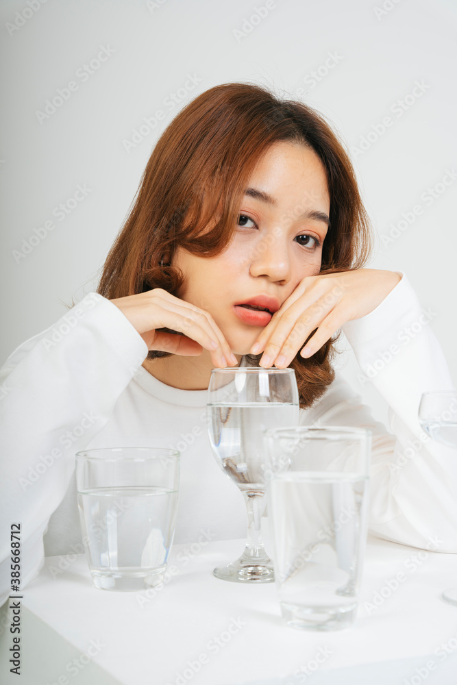 Asian woman with water glasses on table isolate on white background. Asian woman with water glasses on table isolate on white background.
