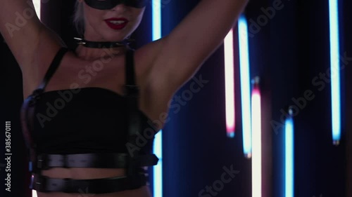Fit woman in underwear dancing passionately near wall with colorful neon lights during performance in dark nightclub
