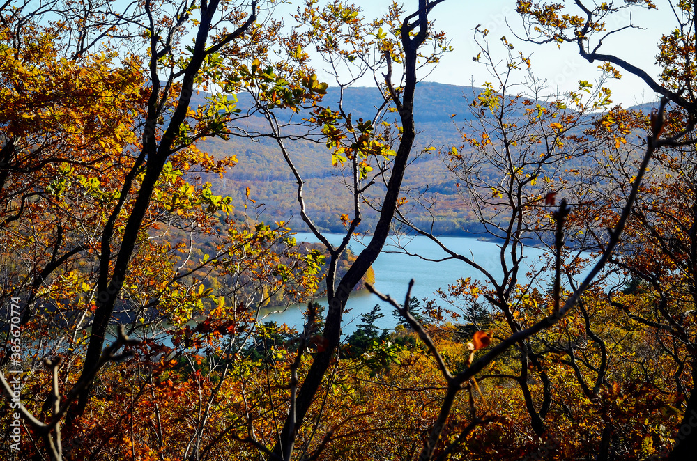 Scenic blue lake surrounded by hills covered with trees in fall colours Scenic blue lake surrounded by hills covered with trees in fall colours