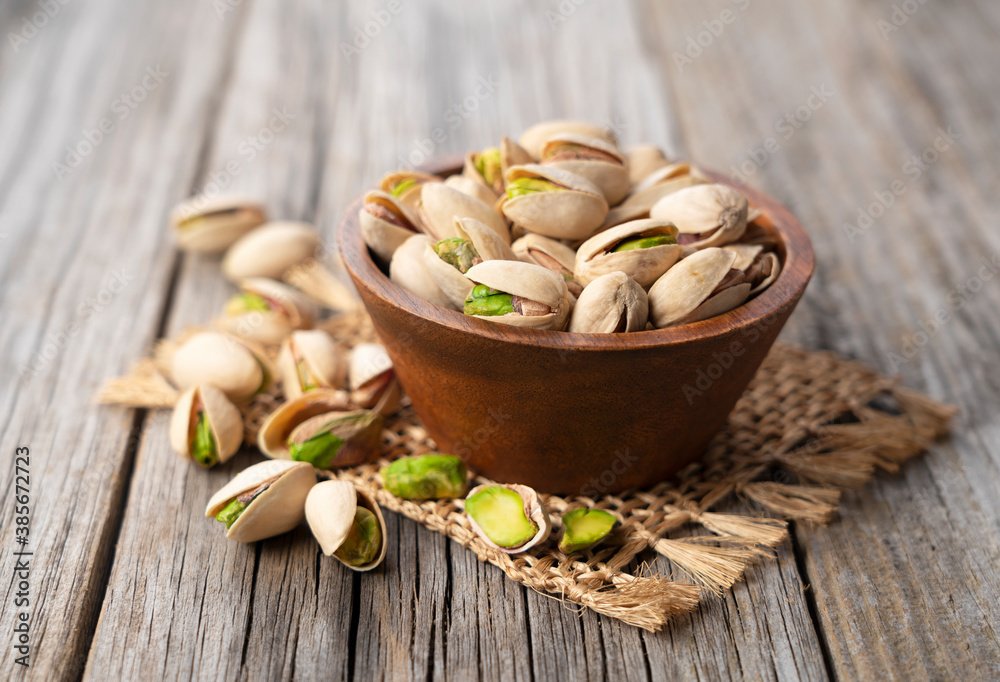Pistachios in a bowl set against an old wooden backdrop Pistachios in a bowl set against an old wooden backdrop