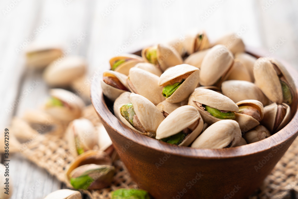 Pistachios in a bowl set against an old wooden backdrop Pistachios in a bowl set against an old wooden backdrop