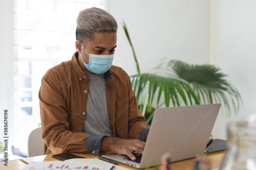 Man wearing face mask using laptop at office Man wearing face mask using laptop at office