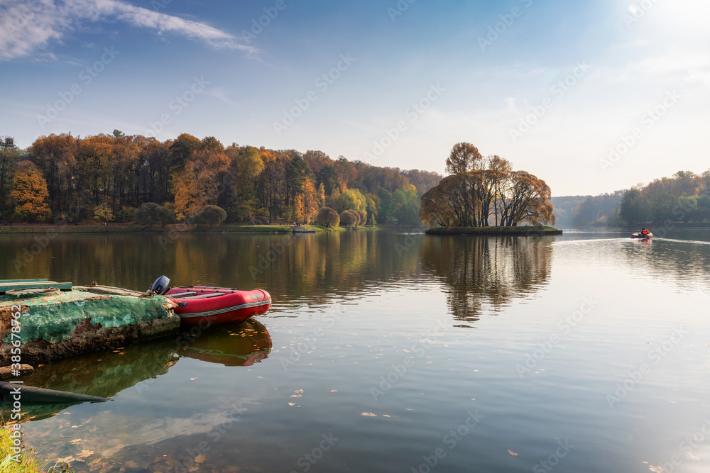 Colorful autumn landscape. Boat on the lake and fall forest.