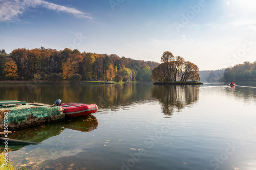 Colorful autumn landscape. Boat on the lake and fall forest.