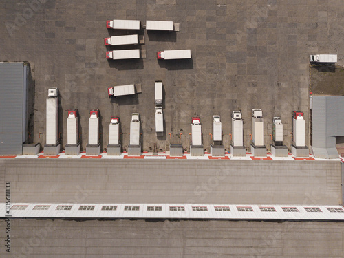 Aerial Top View of White Semi Truck with Cargo Trailer Parking with Other Trucks on Special Parking Lot.